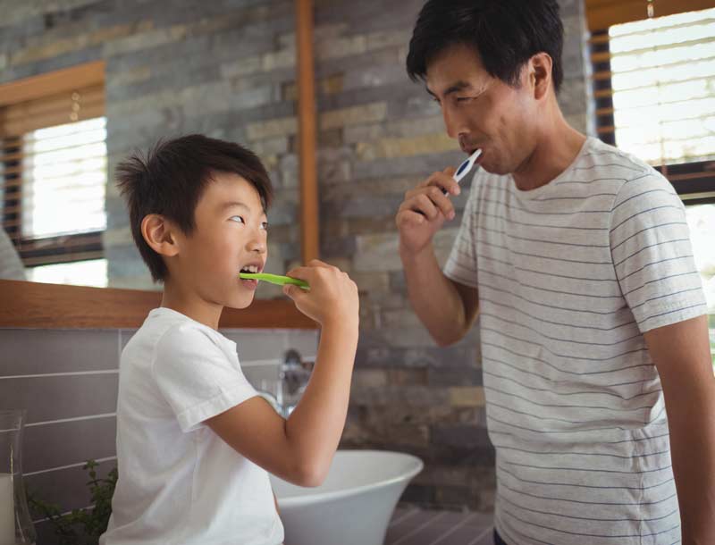 Father brushing teeth with son